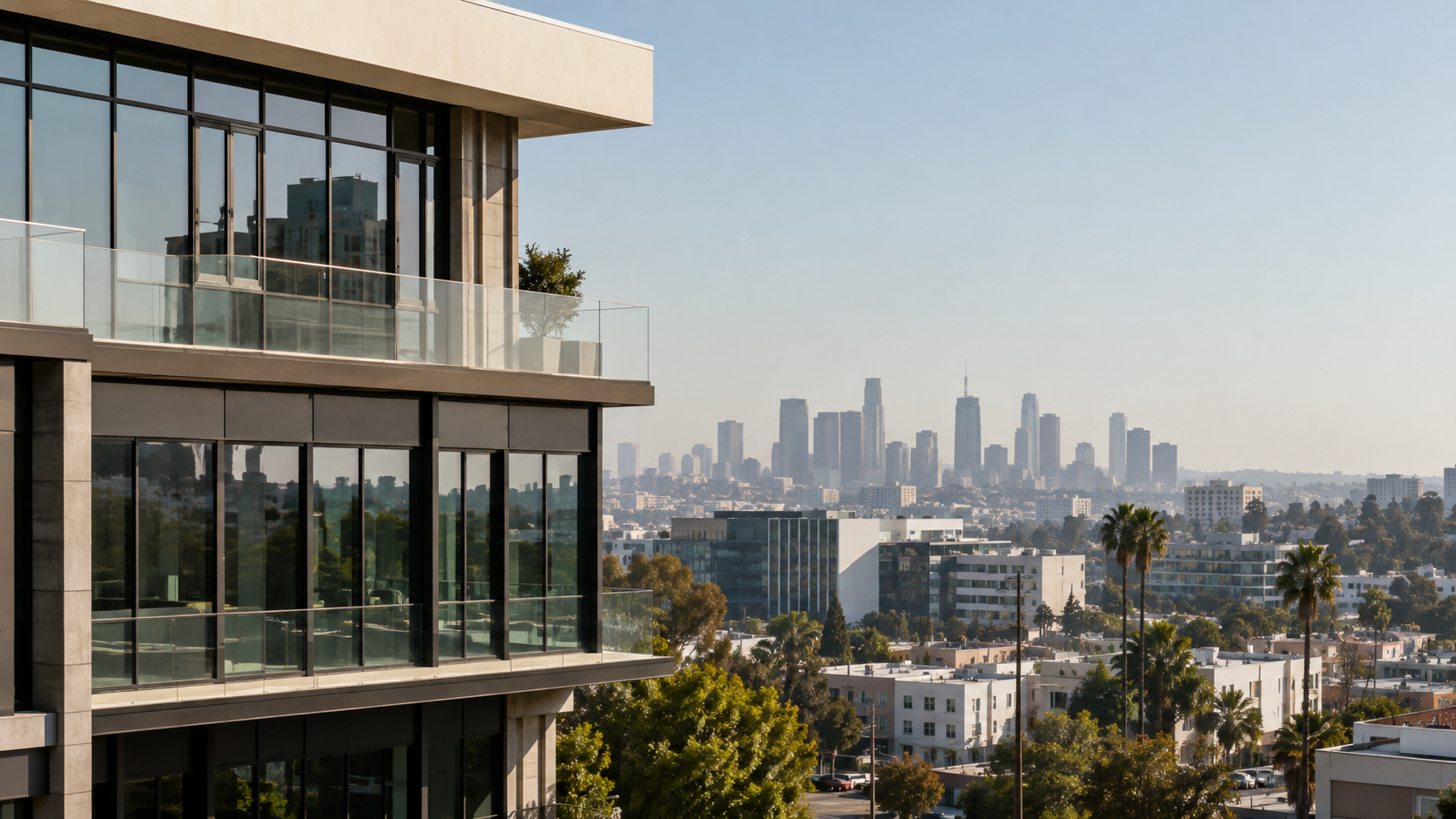 A glass-and-stone commercial building above a Los Angeles neighborhood, the downtown skyline beyond.
