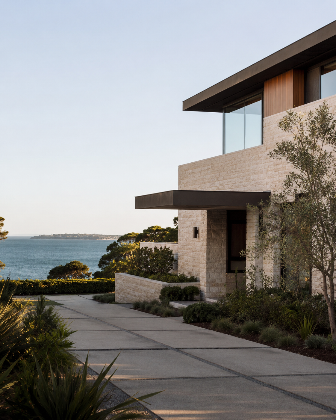 A California coastal house in stone and glass, the sea beyond it.