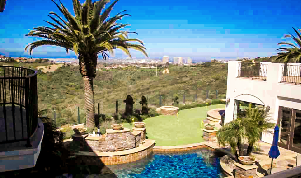 The funded Corona del Mar property: a hillside terrace with a pool, putting green and palm overlooking the coastal skyline.