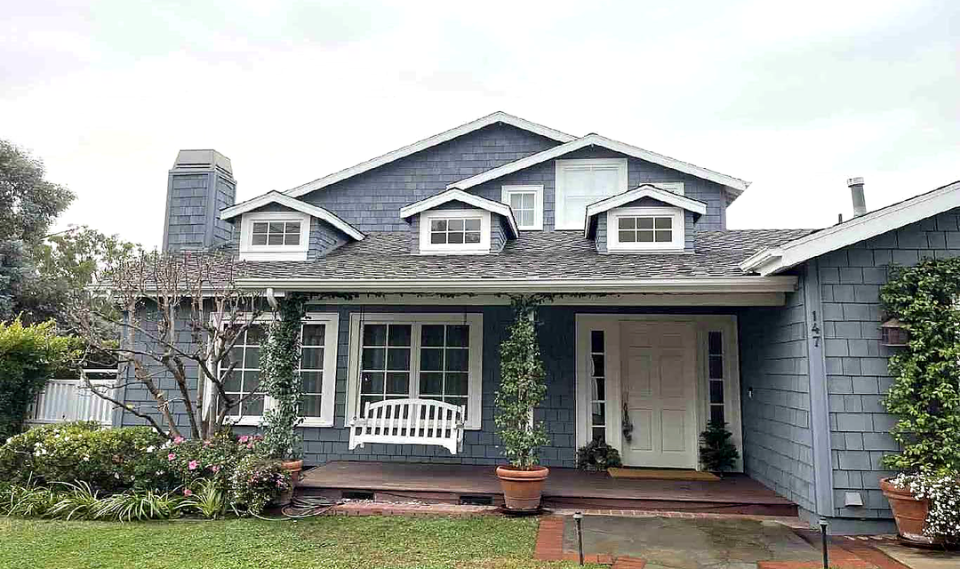 The funded Los Angeles residence: a blue shingle-sided home with dormer windows and a covered porch.